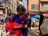 Scooters regularly serve as taxis in the tight streets of Kathmandu. This is probably not a taxi with a woman driver!
